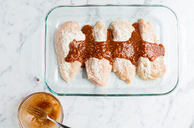 chicken breast with BBQ sauce over top in a baking dish
