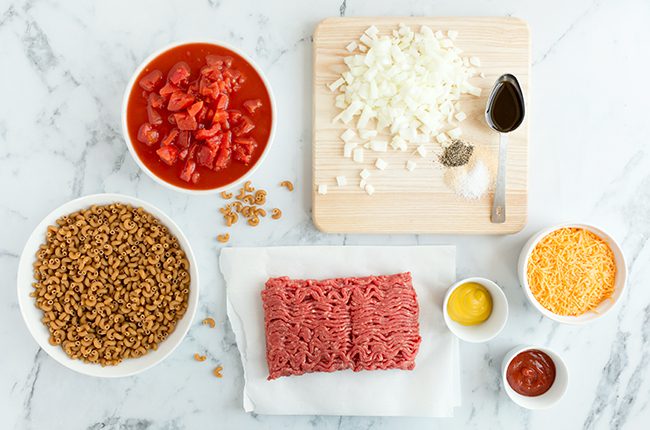 Ingredients for cheeseburger casserole sitting on a marble counter