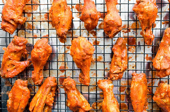 Overhead picture of a baking tray with wire rack holding buffalo chicken wings that have been baked