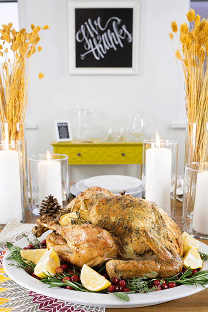Roasted Thanksgiving turkey sitting on a white platter on table with give thanks sign in background