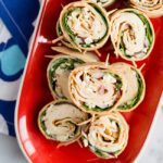 Up close picture of a red platter filled with buffalo chicken pinwheels appetizer
