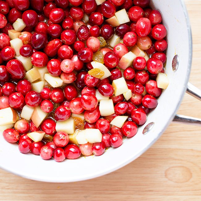 Up close image of a colander filled with cranberries apples and raisins for homemade cranberry sauce
