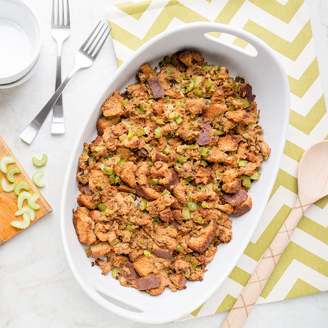 Overhead picture of white casserole dish on green and white cloth filled with sage and onion stuffing