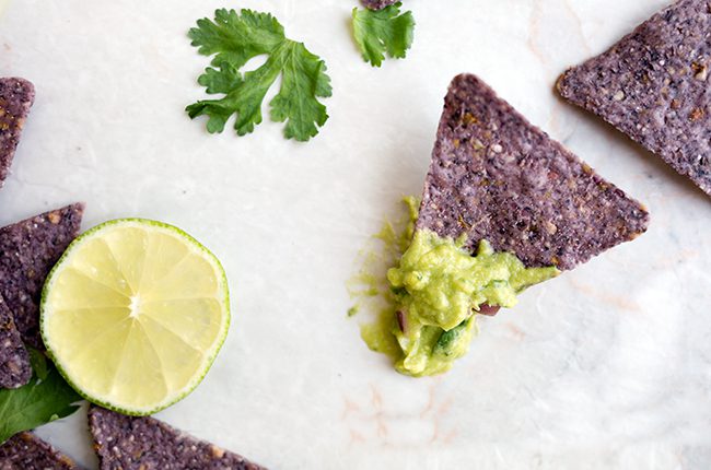 Overhead picture of a blue corn tortilla chip with guacamole