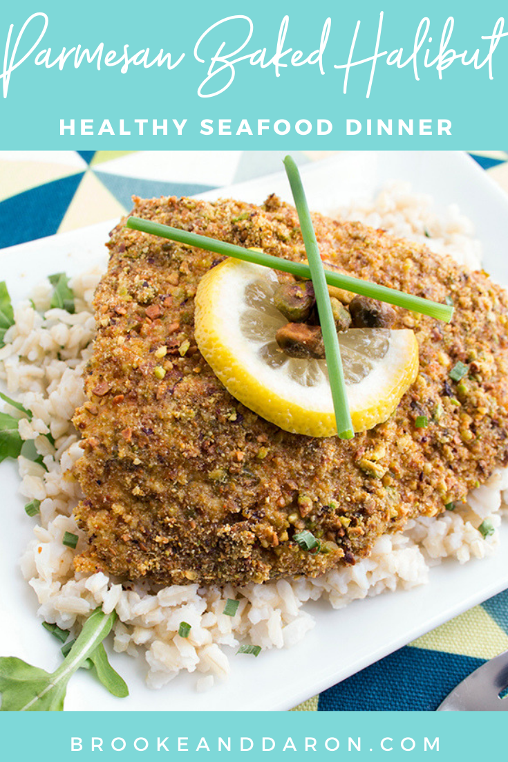 A piece of parmesan halibut sitting on top of rice on a white plate with lemon slice on top