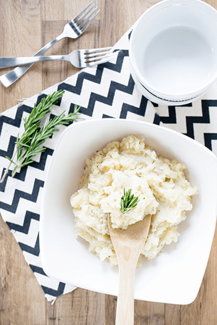 A large white bowl sitting on a black and white chevron print napkin filled with parsnip mash with potatoes and rosemary