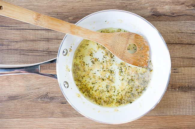 A saucepan filled with butter and herbs for parsnip mash
